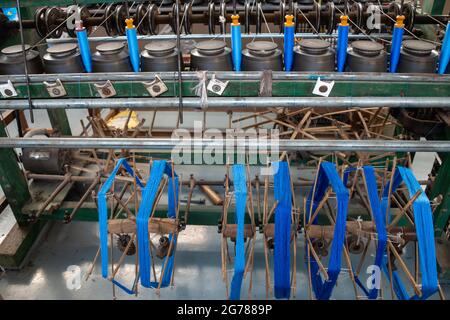 Skeins of blue silk being spooled on to bobbins for use in traditional weaving of cloth, Myanmar Stock Photo