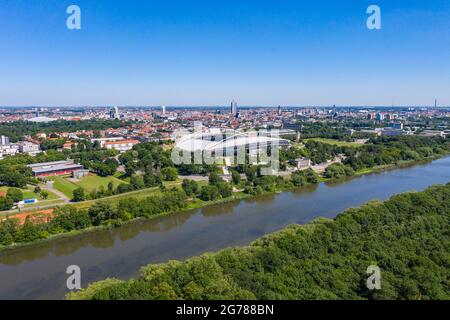 14 June 2021, Saxony, Leipzig: The Red Bull Arena is located on the edge of the city centre, directly on the Elster flood bed. The home ground of RB Leipzig is being rebuilt. The spectator capacity increases from 42,558 to 47,069 standing and seated. The outside of the stadium is enclosed with a soundproof facade. The embankment of the former Zentralstadion, which encompasses the arena, was cut open behind the historic bell tower to make room for a new entrance. RB Leipzig is investing a good 60 million euros in the conversion by 2022. (Aerial view with drone) Photo: Jan Woitas/dpa-Zentralbild Stock Photo