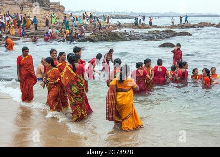 Group of hindu female worshippers wearing red clothing bathing in the
