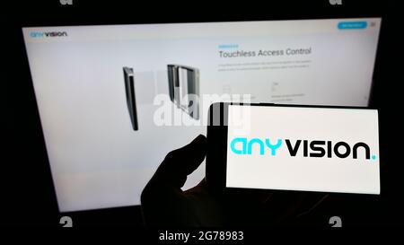 Person holding cellphone with logo of company AnyVision Interactive Technologies on screen in front of business webpage. Focus on phone display. Stock Photo