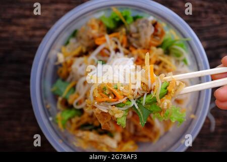 Top view close up hand hold chopsticks pick up food from serving from order online in plastic bowl,  fried spring rolls with vegan rice noodles Stock Photo