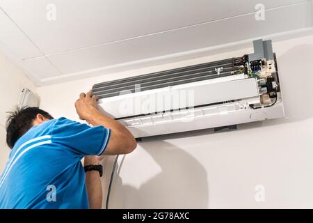 Technician installing indoor air conditioner condenser unit on wall Stock Photo