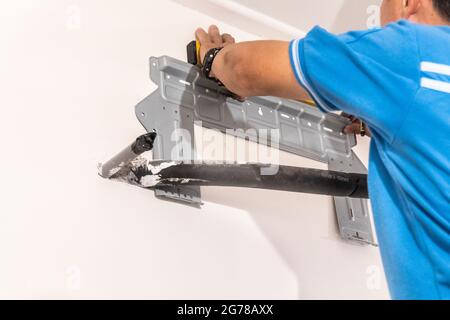 Technician installing wall bracket of air conditioning condenser unit Stock Photo