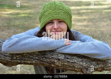 Girl in grey jumper and warm green hat smiling