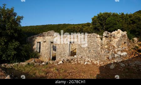 Ionian Islands, Ithaca, island of Odysseus, northwest, mountain village Exogi, ruins of a single standing stone house, behind it forest, blue sky Stock Photo