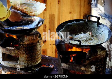 Two coal stove in bright red for people make Vietnamese pancake at sidewalk restaurant, yellow crispy cake is popular street food on  at outside sidew Stock Photo