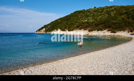 Ionian Islands, Ithaka, island of Odysseus, near Vathi, Filiatro Beach, fine pebble beach, man in the water, in the background few other bathers, on the left at the edge of the picture is a small sailing boat at anchor Stock Photo