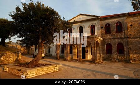 Ionian Islands, Ithaka, island of Ulysses, Katharon monastery, 566m above sea level, dedicated to the Virgin Mary, built 1696, exterior view, main entrance and facade in the last evening light, in front of it a tree enclosed by a small wall Stock Photo