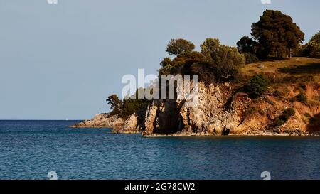 Ionian Islands, Ithaca, island of Odysseus, northeast coast, Marmakas Bay, overgrown rocky coast, blue sea, light blue sky Stock Photo