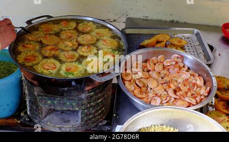 Vietnamese mini shrimp pancake and raw material, make yellow crispy cake, people make popular street food on coal stove at outside sidewalk restaurant Stock Photo