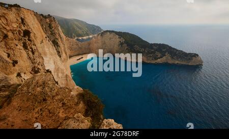 Zakynthos, Paralia Navagio, Shipwreck Beach, view from above over bay and large part of the deserted beach, shipwreck MV Panagiotis, water directly in front of the beach turquoise, water in the bay blue, sky cloudy Stock Photo