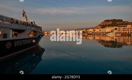 Zakynthos, Zakynthos town, morning light, port, excursion boat in the picture in the shadow, mirror-smooth, dark blue sea in the middle distance, morning skyline of Zakynthos town and castle hill Stock Photo