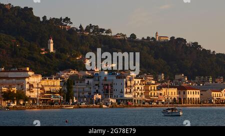 Zakynthos, Zakynthos City, morning light, partial view of the skyline of Zakynthos City, seen across the sea from the southeast, boat in the foreground, Panagia Pikridiotissa church on the left in the picture, Agia Paraskevi church on top right on a hill Stock Photo