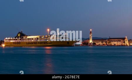 Zakynthos, Zakynthos town, night shot, evening shot, harbor, Zante ferry illuminated in the middle distance, night blue water in the foreground, illuminated church of Agios Dionysios right behind the ferry, blue night sky, festive church tower Stock Photo