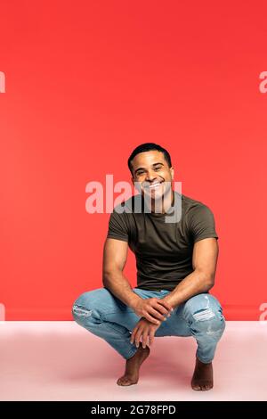Hispanic dancer with casual clothes smiling and posing in studio shot against red background. Stock Photo