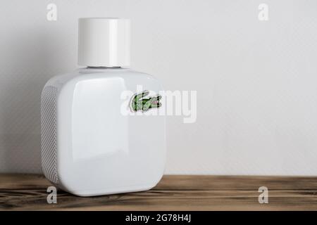 Minsk, Belarus 07.05.2021: White perfume bottle with Lacoste logo on wooden surface on white background Stock Photo