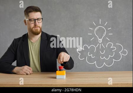 Young businessman pushes a red creativity button to launch an idea light bulb rocket Stock Photo