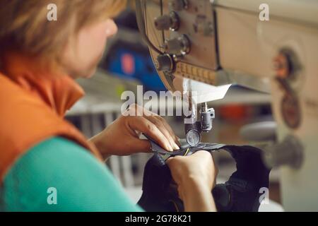 Shoemaker hands in focus sewing leather for making shoe using needle machine Stock Photo