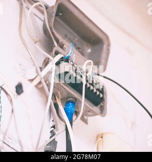 An old junction box with wires on a light wall. Selective Focus Stock Photo