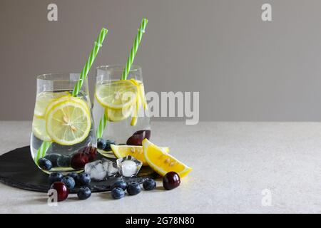 Cold drinks in small bottles. Cherries and lemon lemonade or cocktail. Stock Photo
