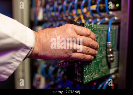Close-up of unrecognizable server engineer installing server component into rack cabinet Stock Photo
