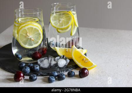 Cold drinks in small bottles. Cherries and lemon lemonade or cocktail. Stock Photo