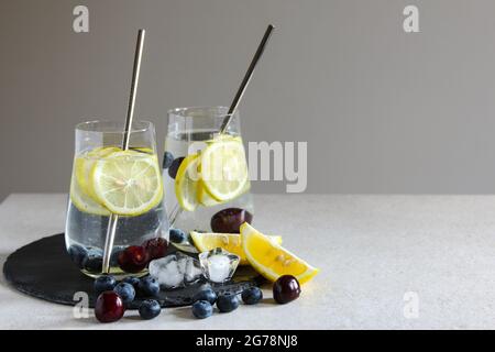 Cold drinks in small bottles. Cherries and lemon lemonade or cocktail. Stock Photo