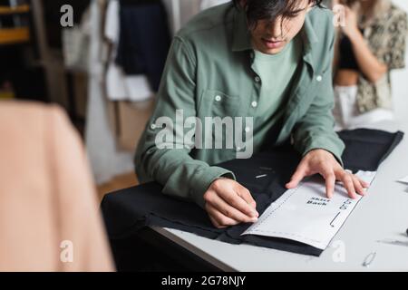young fashion designer working with sewing pattern and fabric in tailor shop Stock Photo