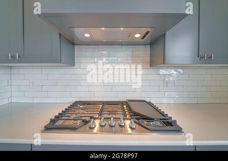 Cooktop with burners fixed on the kitchen countertop of home with exhaust hood Stock Photo