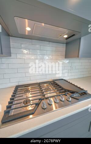 Cooktop stove with burners fixed on kitchen countertop against white tiles Stock Photo