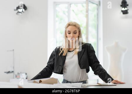 trendy fashion designer looking at sewing patterns while working in tailor shop Stock Photo