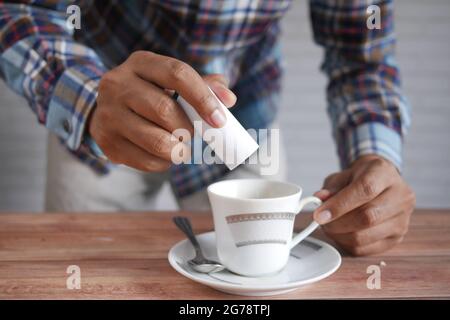 young man putting artificial sweetener in tea, Stock Photo