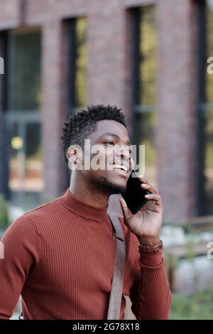 Cheerful African businessman holding phone by ear during communication Stock Photo