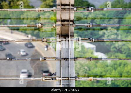 tension steel cables with steel fasteners, a close up view of detail of clamps system on glass bridge with tensioners engineering construction stainle Stock Photo