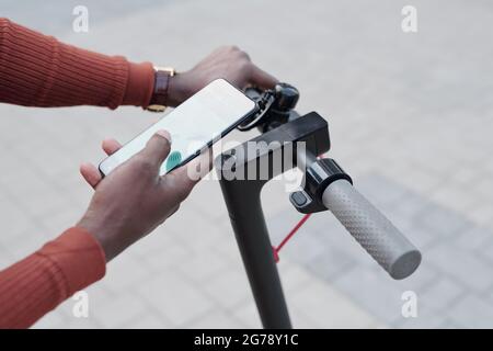 African man using mobile app to pay for scooter rent outdoors Stock Photo