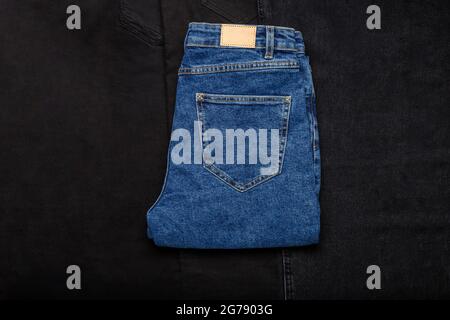 Blue jeans denim pants on black denim jeans textile texture fabric background. Top view. Stock Photo