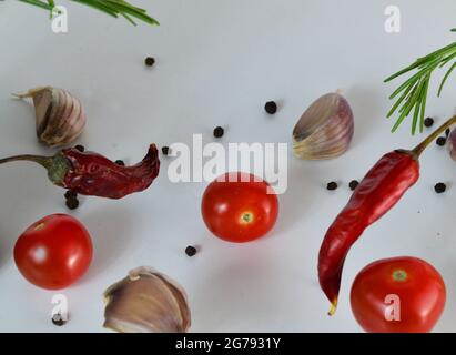 Garlic falling in air with pepper and herbs like rosemary and basil leaves on white background. Spicy food concept. abstract background, no focus. Stock Photo