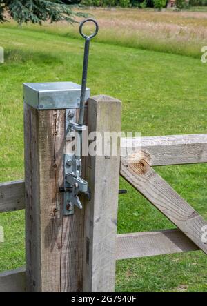 Metal gate locking mechanisim mounted on a wooden gate post with metal cap Stock Photo