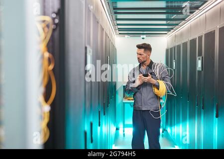 Portrait of bearded network engineer inspecting server room in data center, copy space Stock Photo