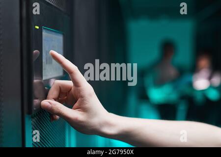 Side view close up of unrecognizable man operating server cabinet via digital control panel in data center, copy space Stock Photo