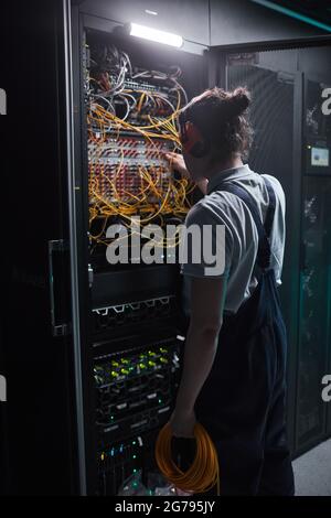 Vertical back view of network engineer in server room during maintenance work in data center Stock Photo