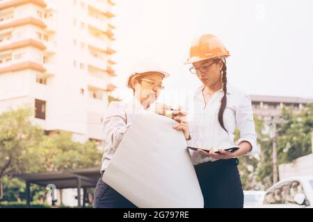Engineers working on a building site holding a blueprints.Construction workers working on a job together meeting for architectural project. Stock Photo