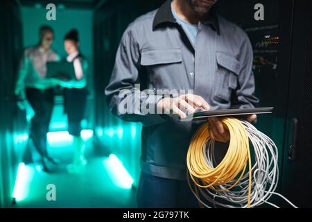 Cropped shot of network engineer using digital tablet in server room during maintenance work in data center, copy space Stock Photo