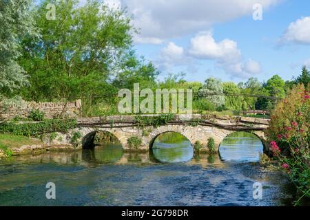 Great Britain, GL Gloucestershire, Bibury near Cirencester, bridge over the River Coln, historic stone bridge, footpath to Arlington Row. The artist and writer William Morris called Bibury 'the most beautiful village in England'. Stock Photo