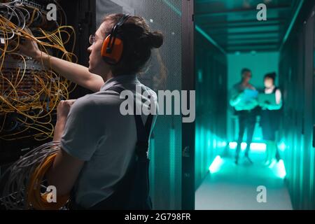Side view portrait of young network engineer in server room doing maintenance work in data center, copy space Stock Photo