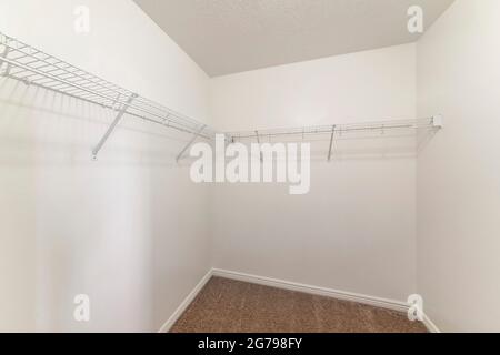 Empty storage room with wall mounted white metal shelves and hooks Stock Photo