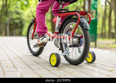 Close-up of a child rides a bicycle with three wheels. Stock Photo