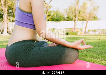 Beauty fitness Beautiful yoga woman practice in a training on pink mat and green park garden background. Stock Photo
