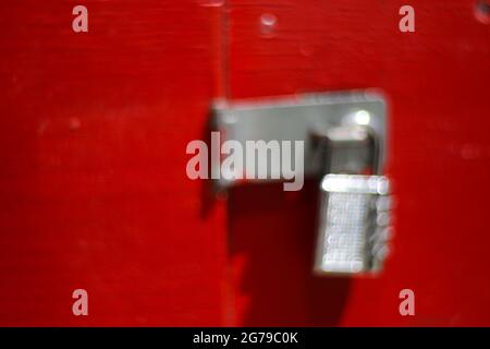 Bolt with combination lock against a red background. Emotional motifs with blurring, background / graphics / composing / real photography without blurring filters Stock Photo