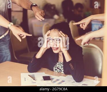 After Discussing the Coworkers pointer finger to a Serious headache Young business woman analyzing graph and chart document on office desk.Dramatic mo Stock Photo